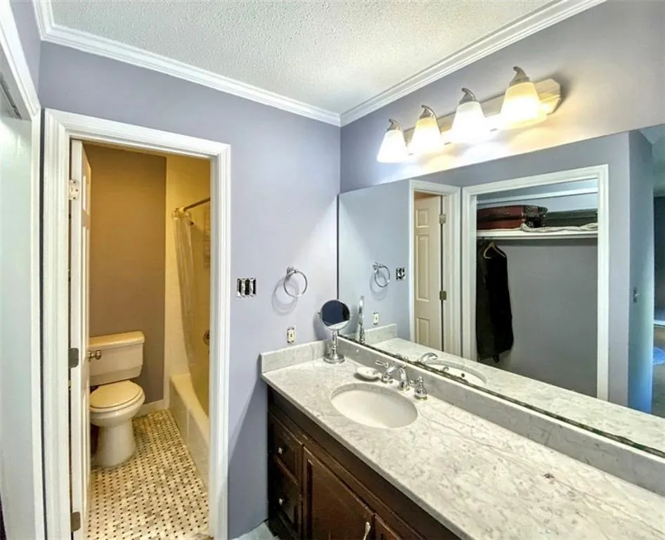 Full bathroom with crown molding, vanity, a textured ceiling, shower / bath combination with curtain, and light tile patterned floors