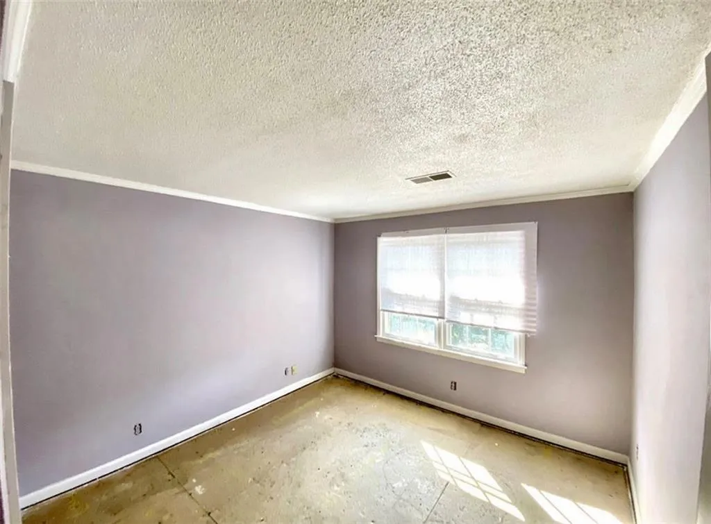 Spare room featuring crown molding and a textured ceiling