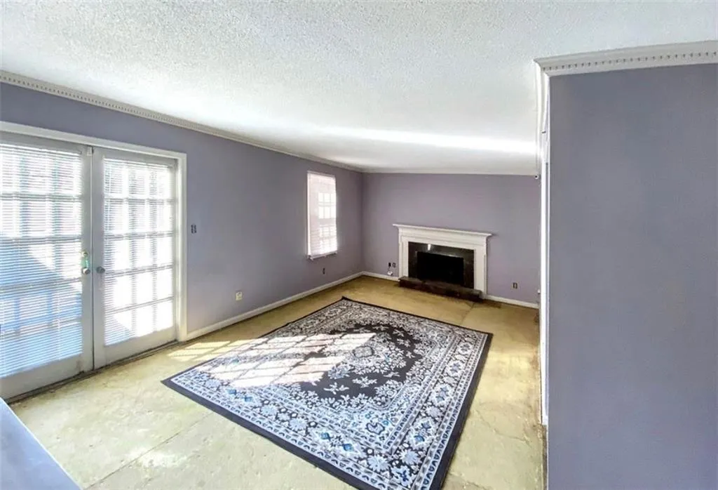 Unfurnished living room featuring a fireplace with raised hearth and a textured ceiling