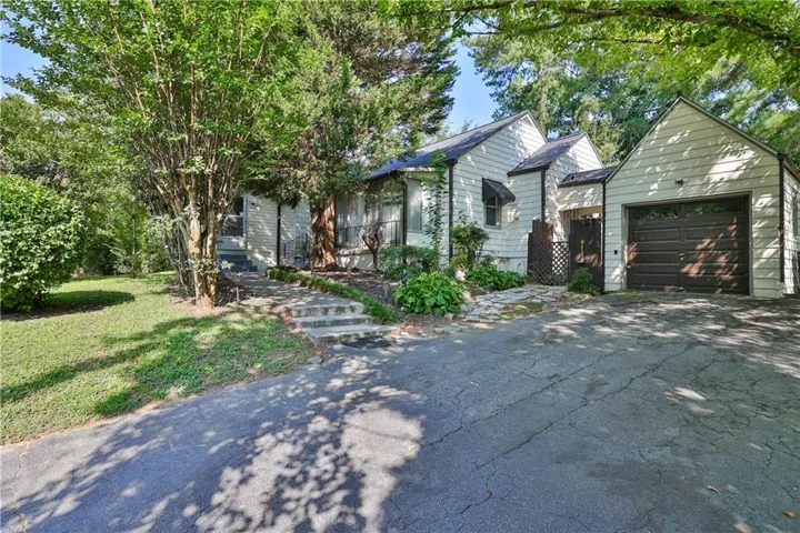 Traditional-style residence with white siding, an attached garage, and a paved driveway