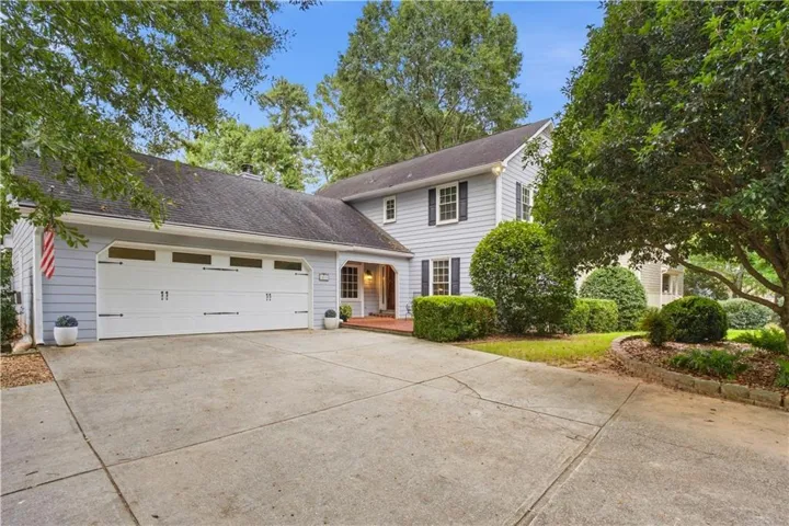 Two-story residence featuring light blue siding with dark shutters, an attached two-car garage, and a concrete driveway