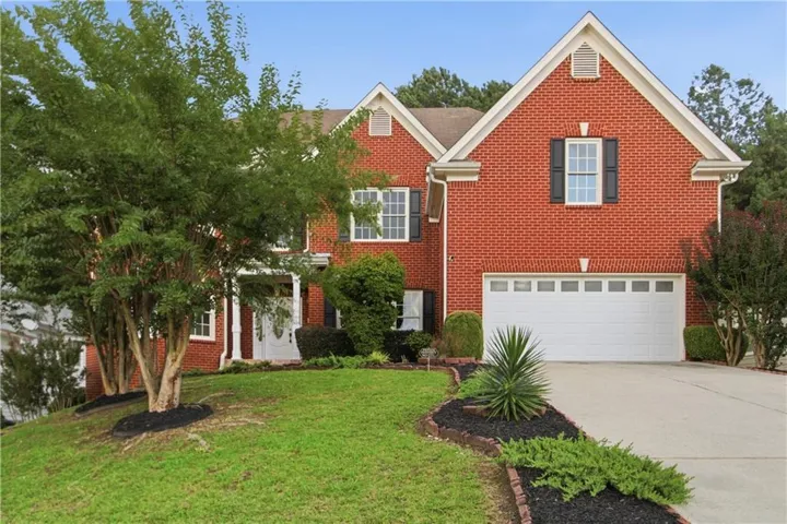 Red brick exterior with white trim, a two-car garage, and a concrete driveway