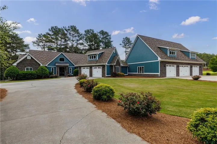 Expansive property featuring a multi-gable roofline and a combination of stone veneer and blue siding