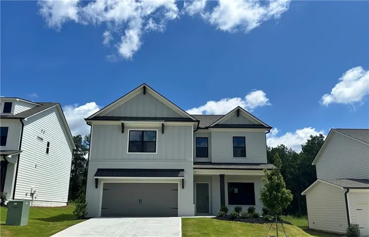 Two-story exterior with light-colored siding, black-framed windows, and a two-car garage
