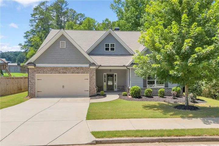 Contemporary ranch-style residence featuring a brick facade, gray siding, and a gabled roofline