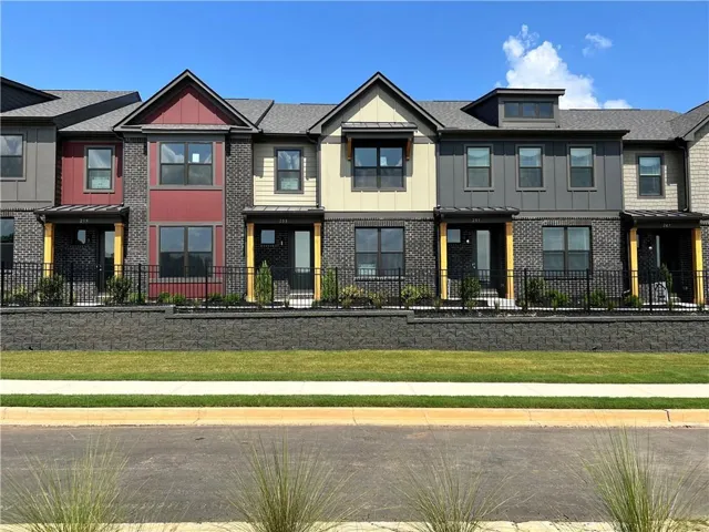 Modern townhome-style residences featuring varied facade textures, black brick detailing, and a black metal fence