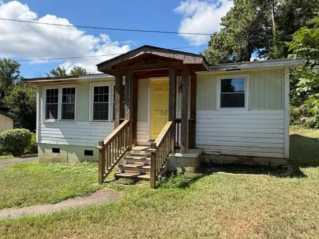 Front exterior featuring a covered porch, wood plank siding, multiple windows, and a concrete pathway