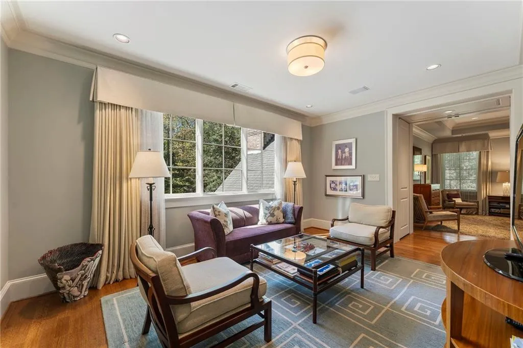 Enter the primary suite through this intimate sitting room with lots of natural light and beautiful views of the wooded preserve surrounding the home.