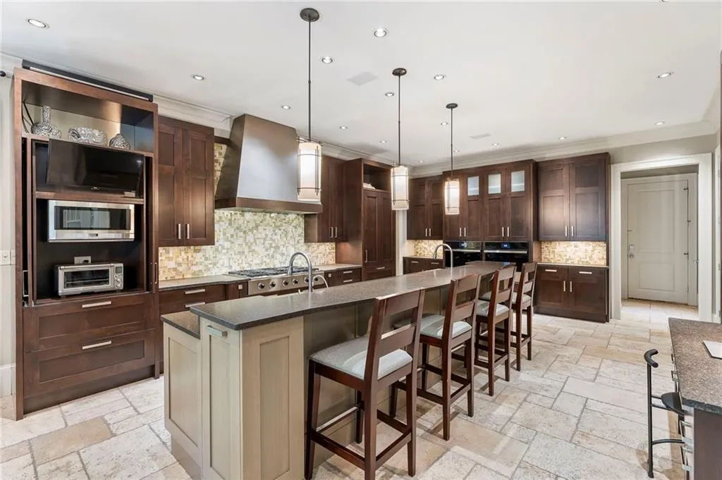 The state-of-the-art kitchen by Design Galleria is a chef’s dream, featuring premier appliances including a Sub-Zero refrigerator and refrigerator drawers, a Dacor six-burner cooktop, dual JennAir ovens, a warming drawer, two dishwashers, and a spacious walk-in pantry.