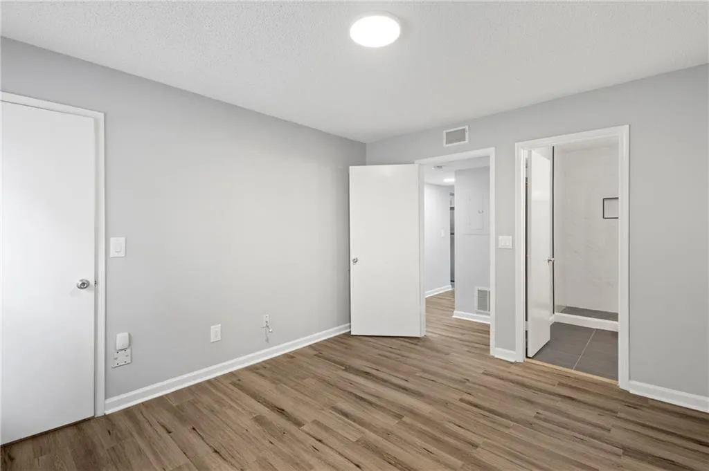 Unfurnished bedroom featuring luxury vinyl floors bathroom, & closet.