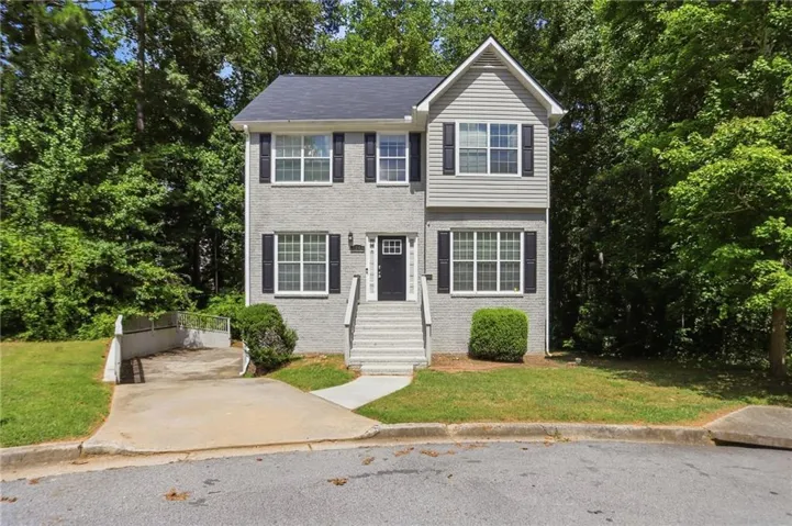 Two-story exterior with a mix of brick and siding, featuring black window shutters and a front entry staircase