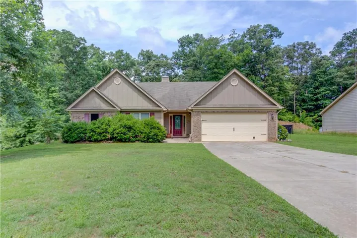 Traditional ranch-style home featuring a two-car garage, brick facade accents, a concrete driveway, and established front landscaping
