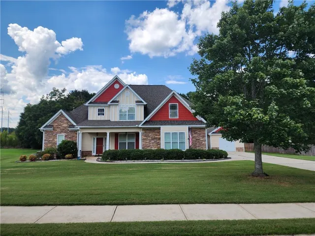 Two-story residence featuring stone and siding exterior, a covered front porch, and a two-car garage