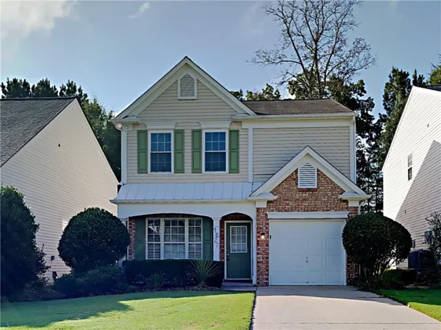 Two-story residence featuring light-colored siding, a prominent gabled roofline, and green shutters