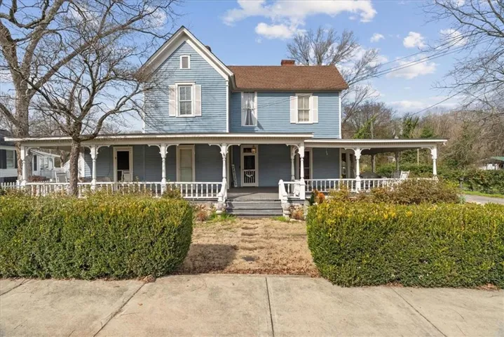 Farmhouse inspired home with a porch and a chimney