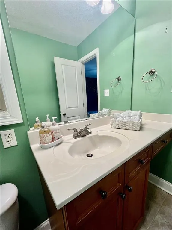 Bathroom with vanity with extensive cabinet space, tile floors, and a textured ceiling