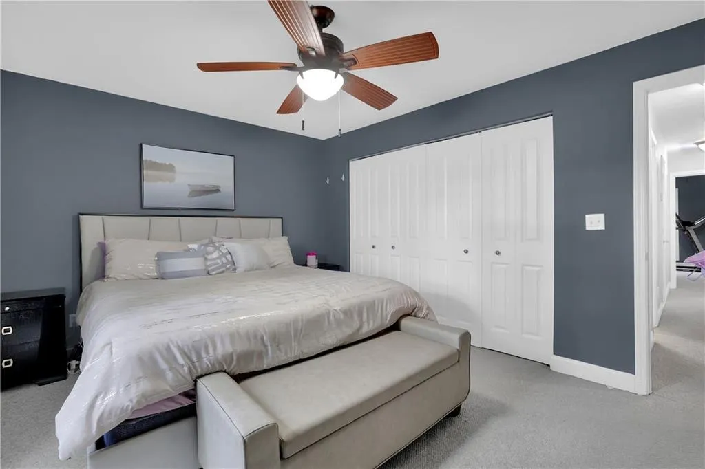 Bedroom with light colored carpet, ceiling fan, and a closet