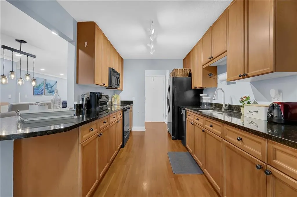 Kitchen featuring sink, hanging light fixtures, rail lighting, range with electric stovetop, and light hardwood / wood-style flooring