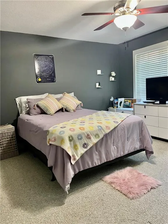 Carpeted bedroom featuring ceiling fan