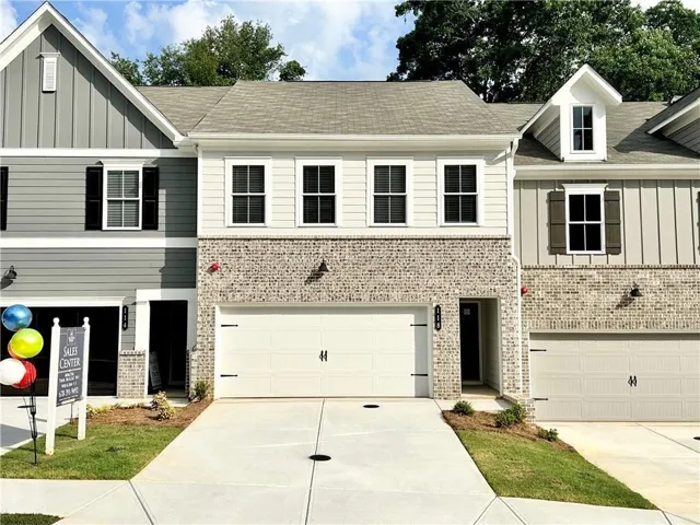 Contemporary townhouse facade featuring a two-car garage, brick and siding exterior, and a gabled roofline