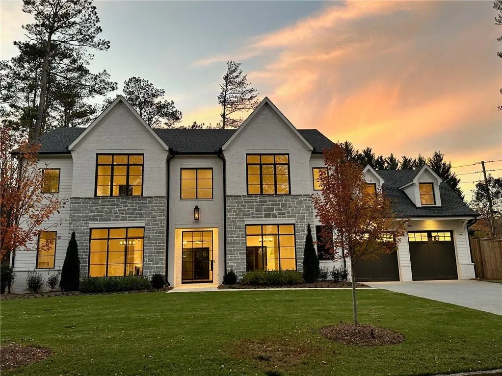 View of front of property featuring stone siding, driveway, and a garage