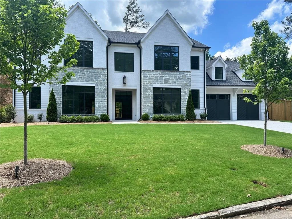 View of front of house featuring a garage, driveway, stone siding, and a front yard