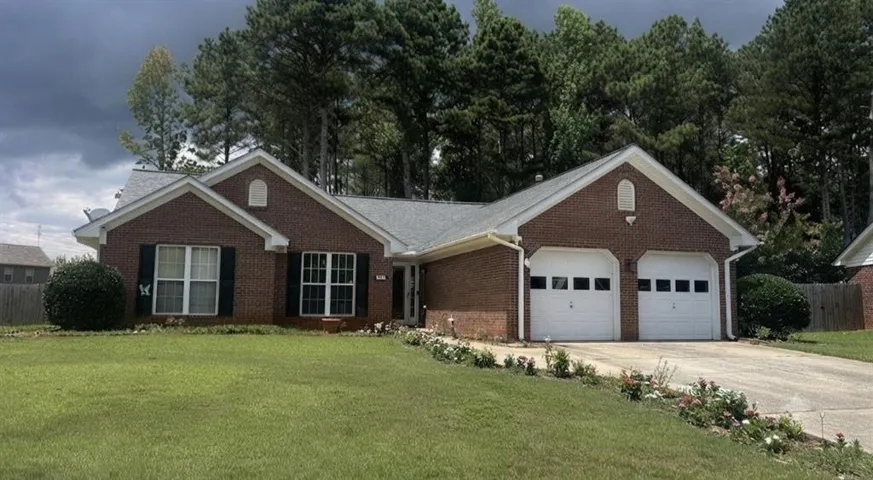 Brick exterior with a gray shingle roof, attached two-car garage, and landscaped front yard