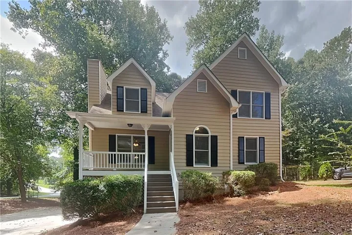 Two-story residence with dormer windows, a covered front porch, and exterior siding