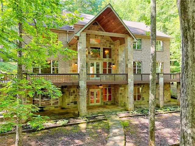 Rear view of house featuring stone siding, french doors, a patio, and a balcony