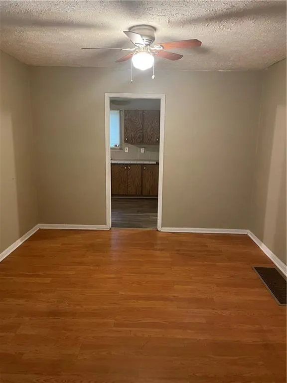Unfurnished room featuring wood finished floors, a textured ceiling, and a ceiling fan