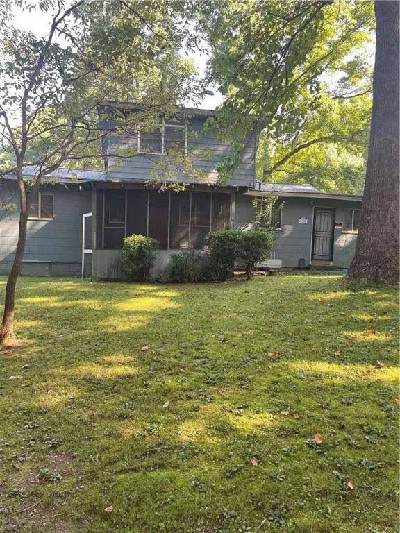 Rear view of house featuring a yard and a sunroom