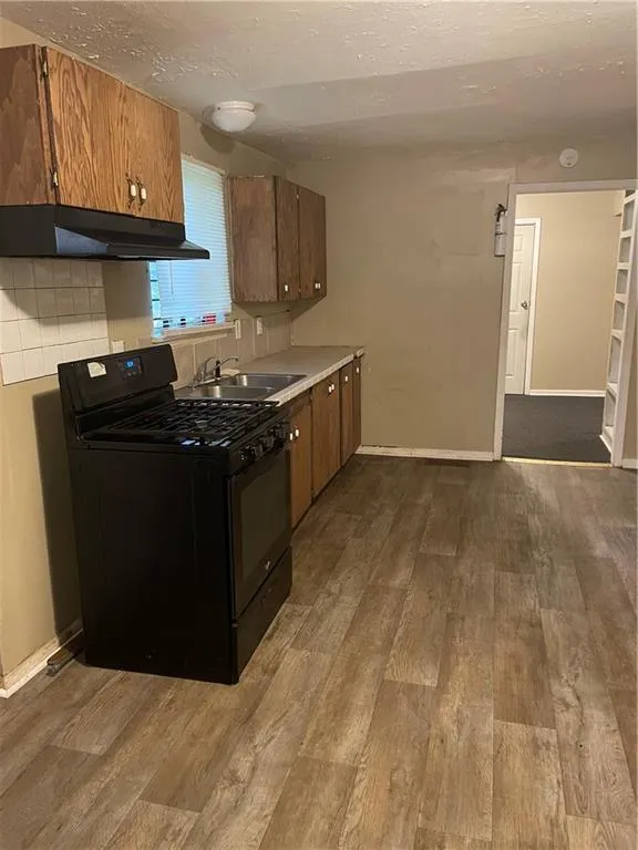 Kitchen featuring range, extractor fan, light wood-type flooring, light countertops, and a textured ceiling