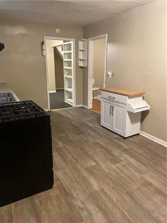 Kitchen with range, dark wood-style flooring, a textured ceiling, and wood counters