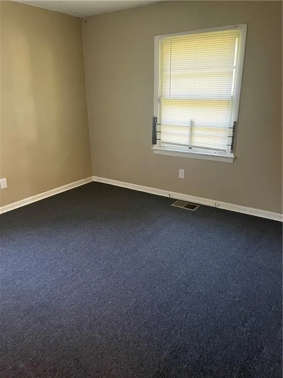 Unfurnished room with baseboards and dark carpet