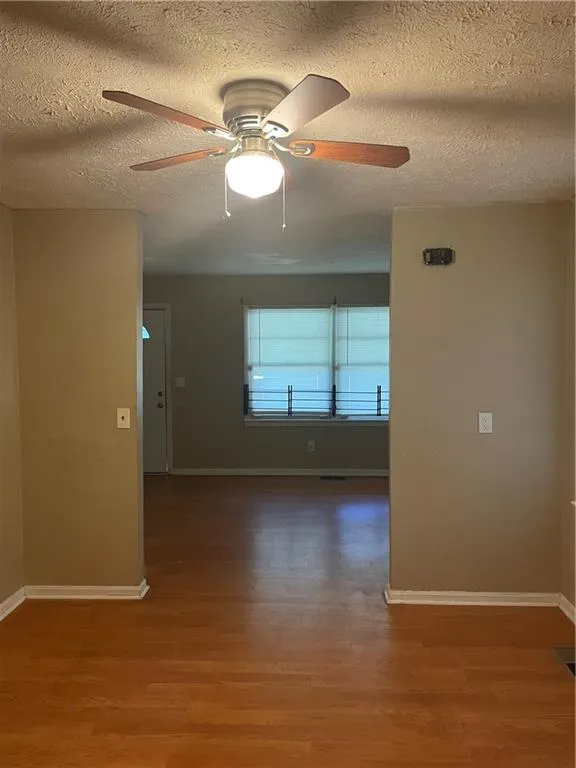 Unfurnished room featuring a textured ceiling, light wood-type flooring, and ceiling fan