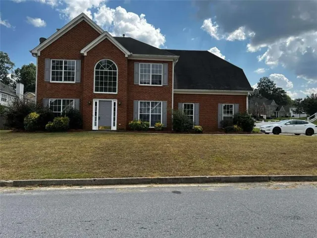 Colonial home featuring a front lawn and brick siding