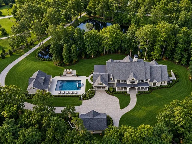 Expansive estate featuring a large main residence, detached garage, private pool with integrated spa, and a natural pond