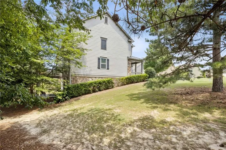 Siding exterior with stone base, multiple windows with dark shutters, and a covered porch
