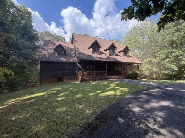 Wood-sided residence with multiple dormer windows, a covered front porch, and an attached screened-in porch