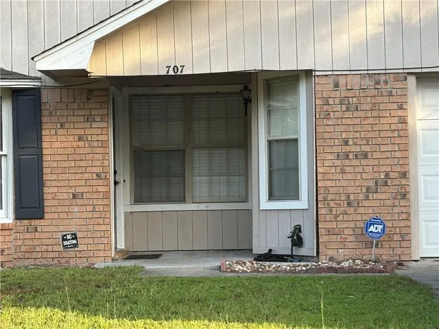 Brick exterior with vertical siding accents, prominent house numbers, and a covered entry