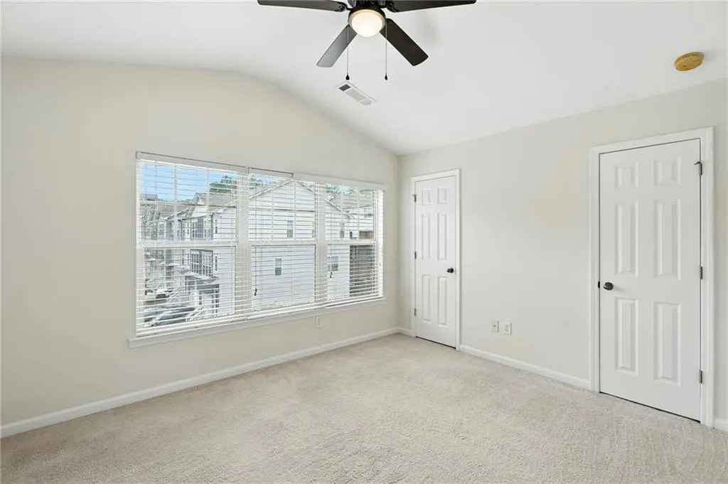 Unfurnished bedroom with carpet, lofted ceiling, and ceiling fan