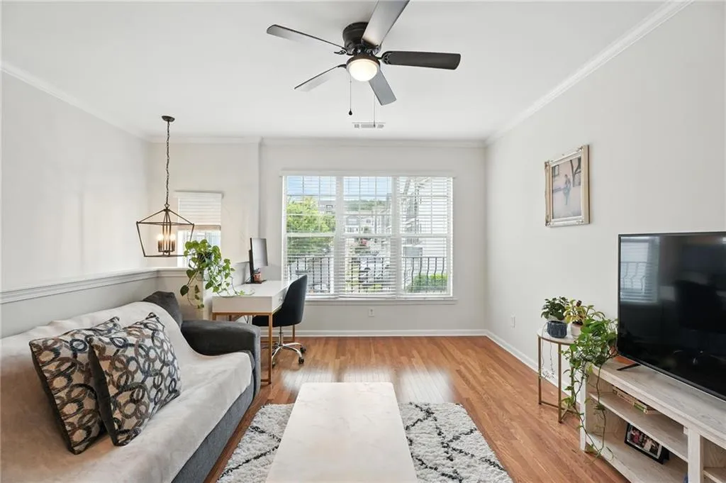 Home office with crown molding, wood finished floors, ceiling fan, and a chandelier