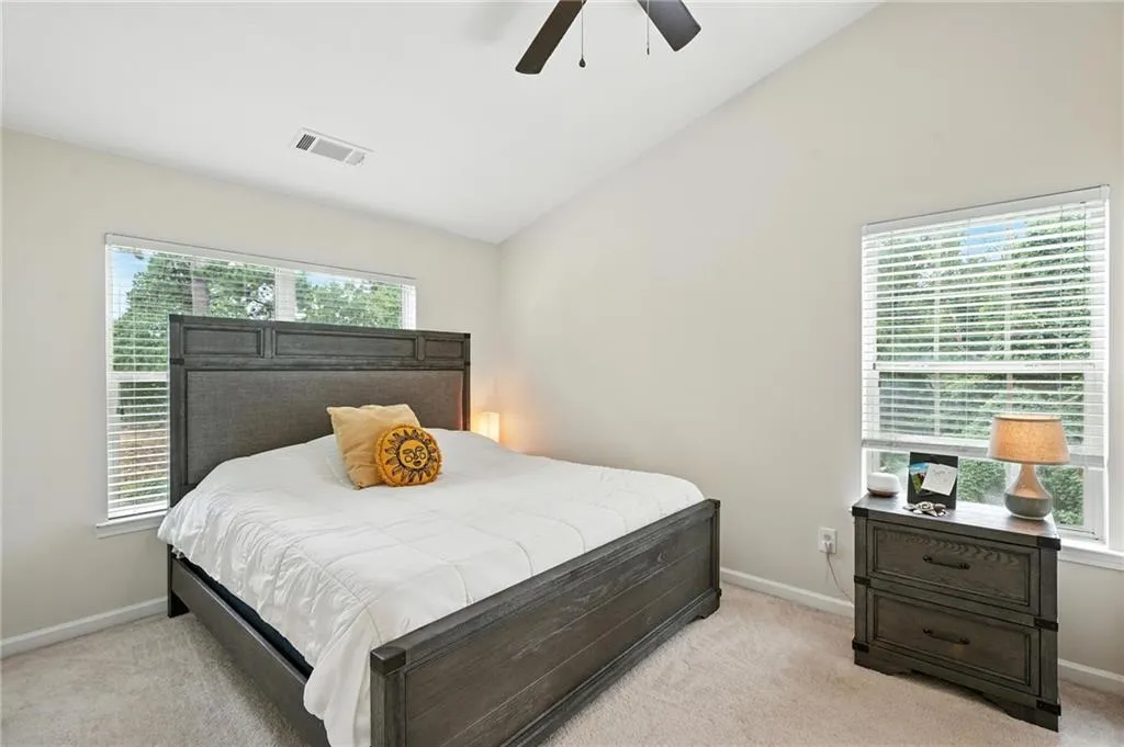 Bedroom featuring lofted ceiling, light colored carpet, and ceiling fan