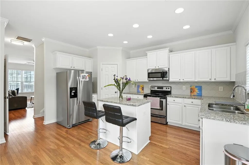 Kitchen featuring healthy amount of natural light, stainless steel appliances, crown molding, a center island, and tasteful backsplash