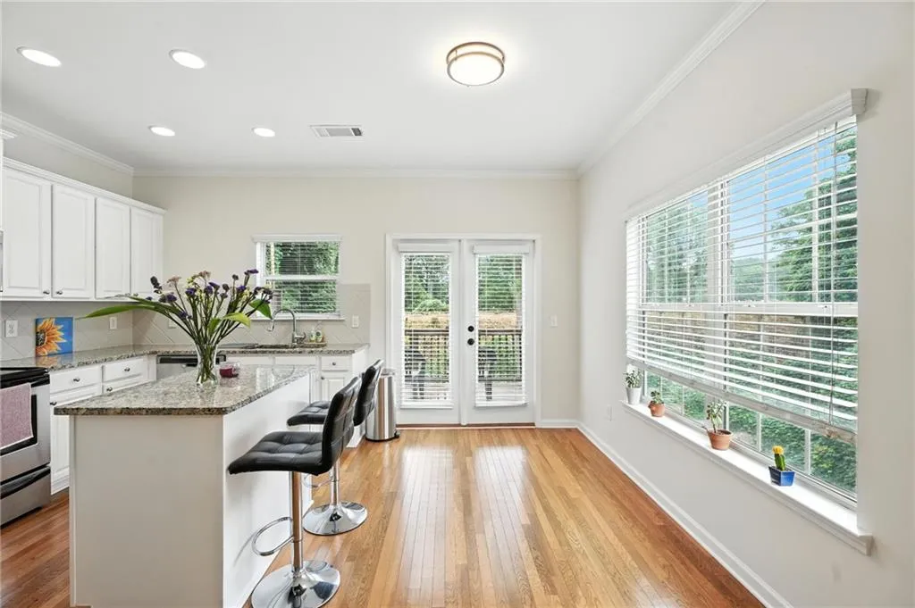 Kitchen with tasteful backsplash, ornamental molding, light wood-style floors, stainless steel electric stove, and a breakfast bar area