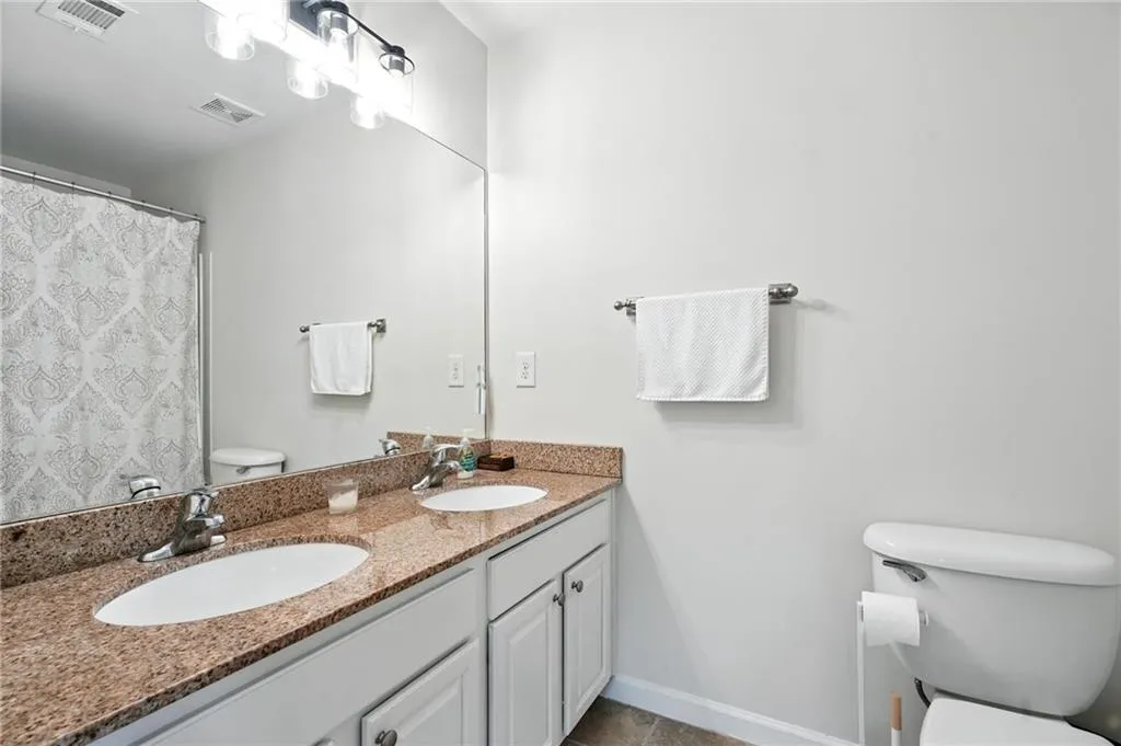 Full bathroom featuring toilet and double vanity