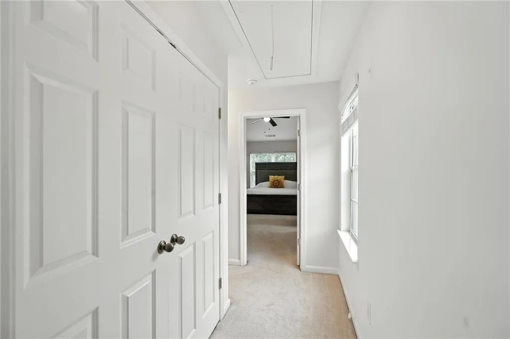 Corridor with attic access and light colored carpet