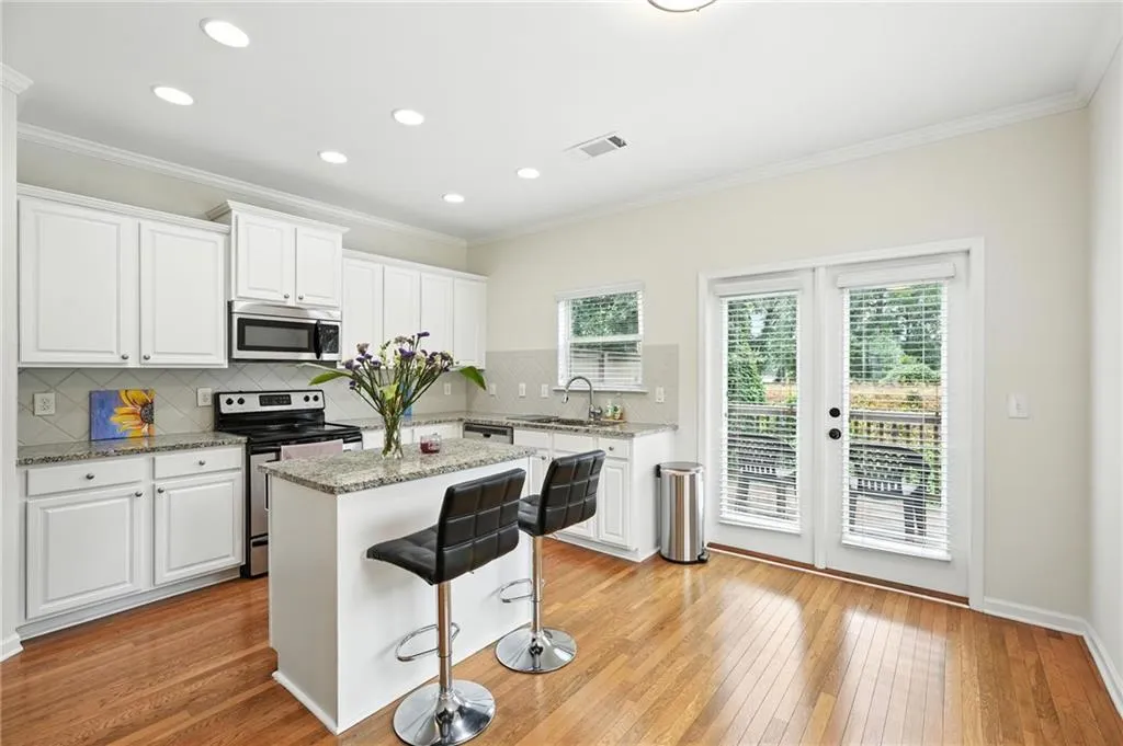 Kitchen featuring appliances with stainless steel finishes, ornamental molding, white cabinets, a kitchen island, and a breakfast bar area