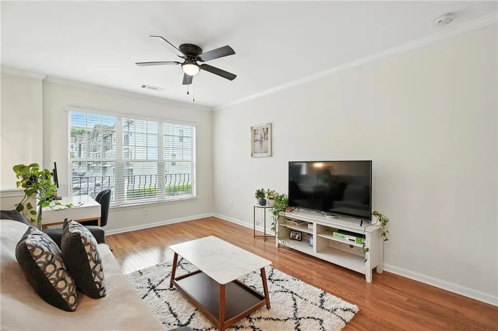 Living room with ornamental molding, wood finished floors, ceiling fan, and a desk
