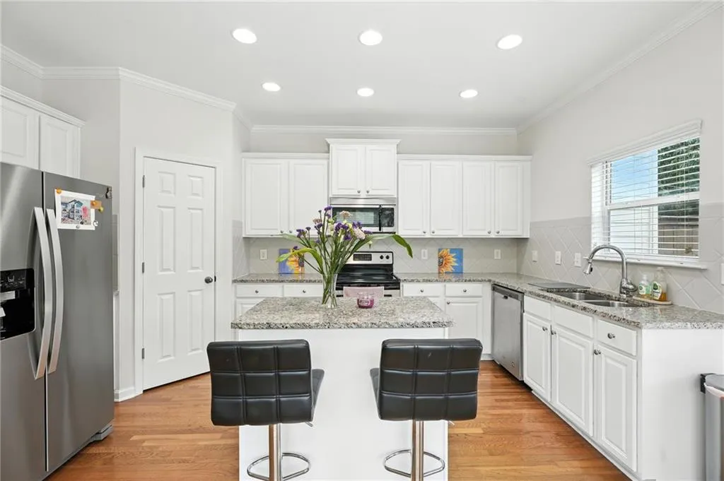 Kitchen featuring appliances with stainless steel finishes, crown molding, white cabinets, a kitchen island, and light wood-style floors